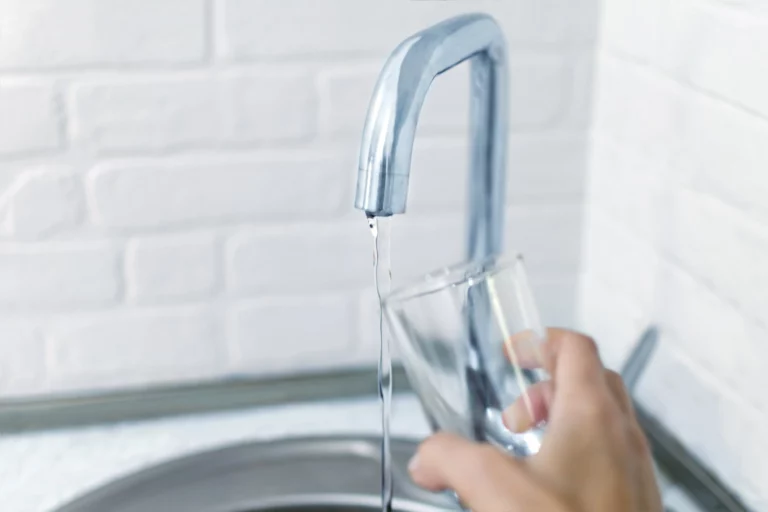 Glas wird mit Trinkwasser aus einem Wasserhahn gefüllt